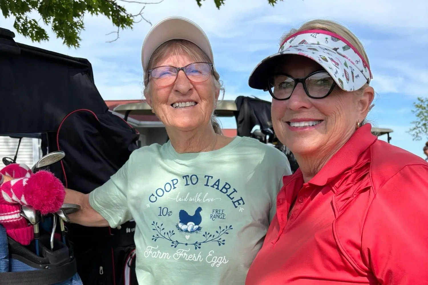 Two ladies league golfers standing together by the carts at Centennial Golf Course