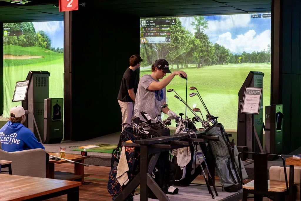 Golfers between simulator bays at On The Green